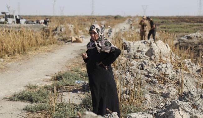 Samira Alloush, searching for her missing son, cries as she watches the Syrian Civil Defense workers inspect clothes found alongside human remains in Otaiba, on the outskirts of Damascus, Syria, Friday, Sept. 19, 2025. (AP Photo/Omar Albam)