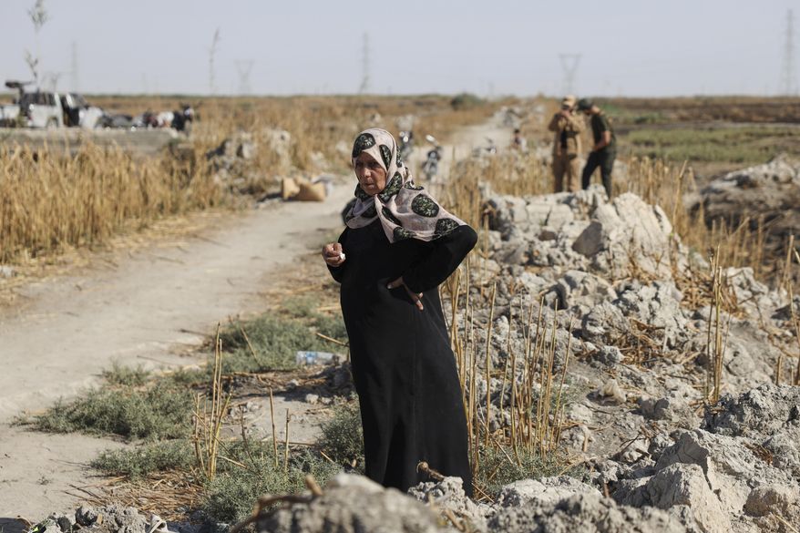 Samira Alloush, searching for her missing son, cries as she watches the Syrian Civil Defense workers inspect clothes found alongside human remains in Otaiba, on the outskirts of Damascus, Syria, Friday, Sept. 19, 2025. (AP Photo/Omar Albam)