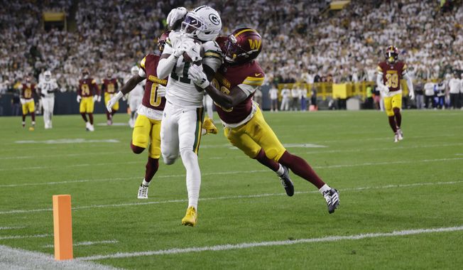 Green Bay Packers wide receiver Jayden Reed (11) makes a catch as Washington Commanders cornerback Mike Sainristil (0) and safety Quan Martin, right, defend before the play was nullified because of a Packers penalty during the first half of an NFL football game Thursday, Sept. 11, 2025, in Green Bay, Wis. (AP Photo/Matt Ludtke)