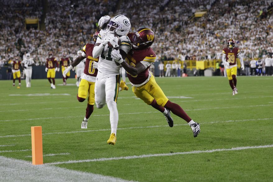 Green Bay Packers wide receiver Jayden Reed (11) makes a catch as Washington Commanders cornerback Mike Sainristil (0) and safety Quan Martin, right, defend before the play was nullified because of a Packers penalty during the first half of an NFL football game Thursday, Sept. 11, 2025, in Green Bay, Wis. (AP Photo/Matt Ludtke)