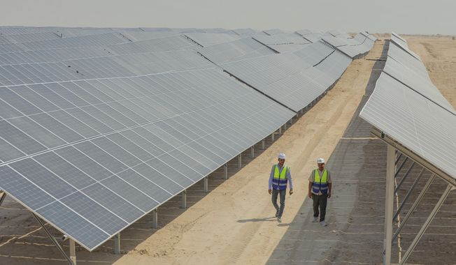 Workers walk between solar panels at a newly opened industrial-scale solar power plant in Karbala, Iraq, Wednesday, Sept. 17, 2025. (AP Photo/Anmar Khalil)