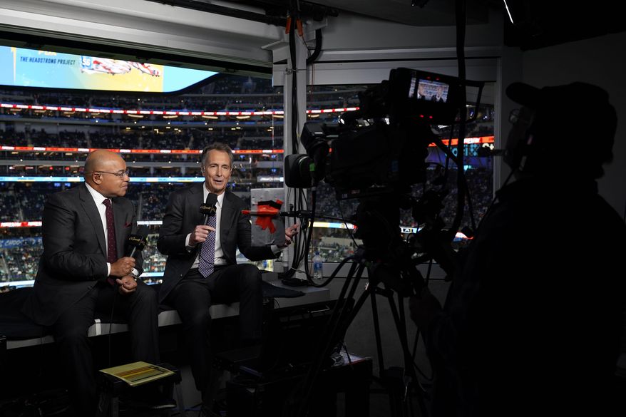 NBC Sports play-by-play announcer Mike Tirico, left, sits next to color commentator Cris Collinsworth before an NFL football game between the Los Angeles Chargers and the Miami Dolphins on Dec. 11, 2022, in Inglewood, Calif. (AP Photo/Jae C. Hong, File)