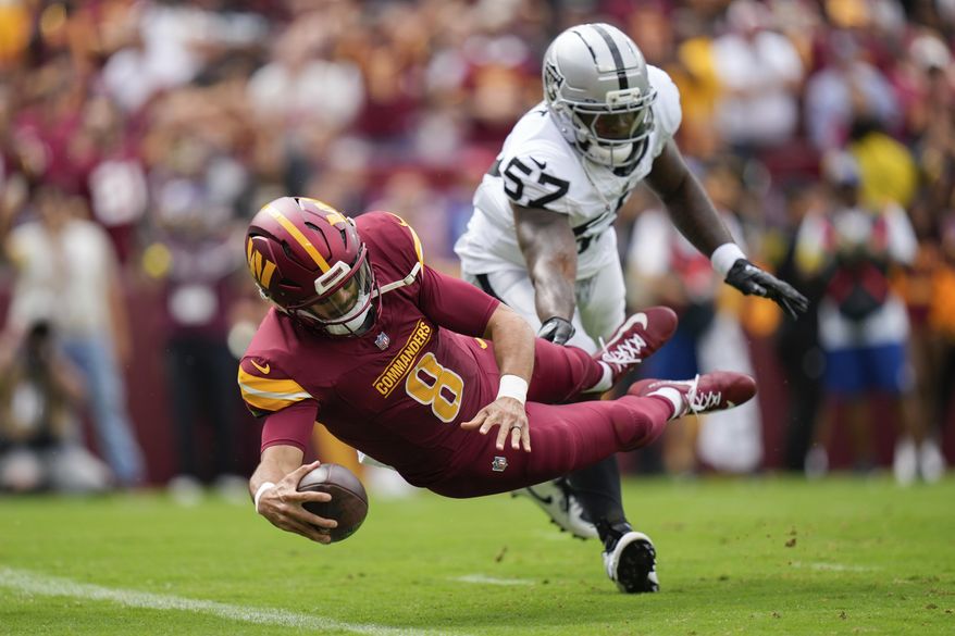 Washington Commanders quarterback Marcus Mariota (8) scores a touchdown as Las Vegas Raiders linebacker Germaine Pratt (57) defends during the first half of NFL football game Sunday, Sept. 21, 2025, in Landover, Md. (AP Photo/Stephanie Scarbrough)
