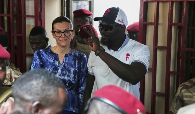 Guinea's interim President, Gen. Mamadi Doumbouya, departs with his wife after casting his vote in the constitutional referendum in Conakry, Guinea, Sunday, Sept. 21, 2025. (AP Photo/Misper Apawu)