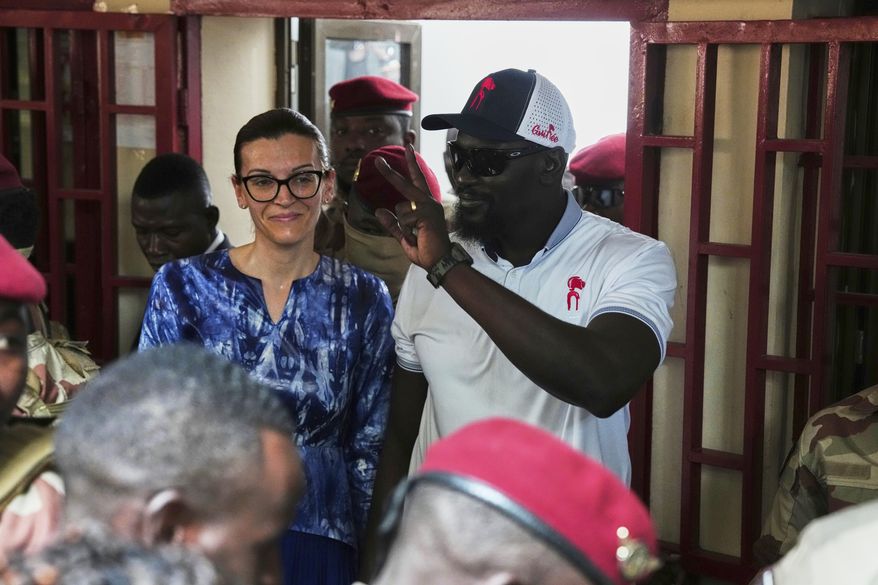 Guinea's interim President, Gen. Mamadi Doumbouya, departs with his wife after casting his vote in the constitutional referendum in Conakry, Guinea, Sunday, Sept. 21, 2025. (AP Photo/Misper Apawu)
