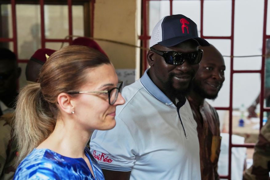 Guinea's interim President, Gen. Mamadi Doumbouya, departs with his wife after casting his vote in the constitutional referendum in Conakry, Guinea, Sunday, Sept. 21, 2025 (AP Photo/Misper Apawu)