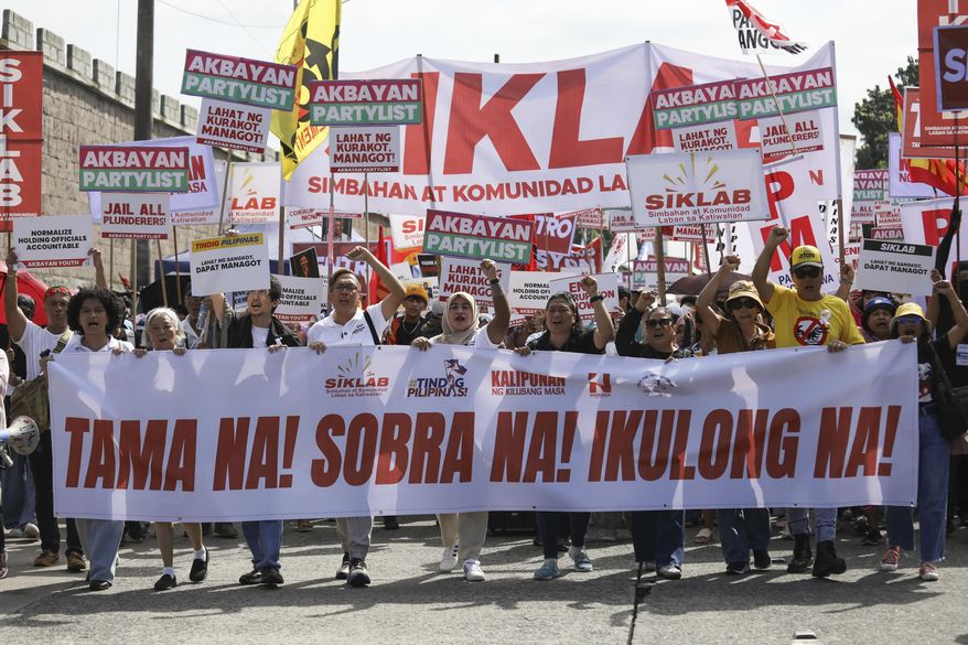 Protesters carry signs as they march during a rally against government corruption at the EDSA People Power Monument in suburban Mandaluyong, east of Manila, Philippines, Sunday. Sept. 21, 2025. (AP Photo/Basilio Sepe)