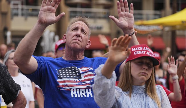 People listen to a worship song in the overflow area outside before a memorial for conservative activist Charlie Kirk, Sunday, Sept. 21, 2025, at State Farm Stadium in Glendale, Ariz. (AP Photo/Jae C. Hong)