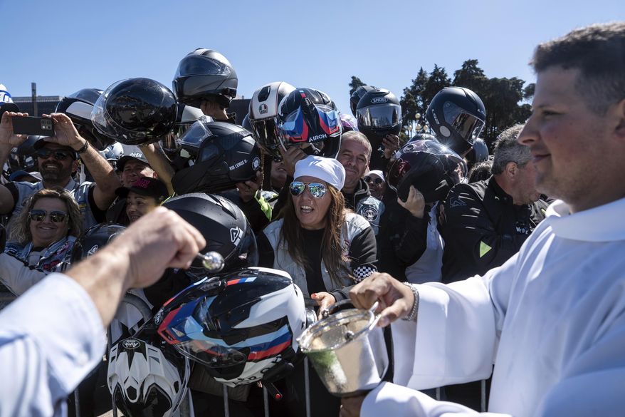 A priest blesses motorcyclists' helmets during the 10th Pilgrimage of the Blessing of Helmets that draws tens of thousands, at the Roman Catholic holy shrine of Fatima, in Fatima, Portugal, Sunday, Sept. 21, 2025. (AP Photo/Ana Brigida)