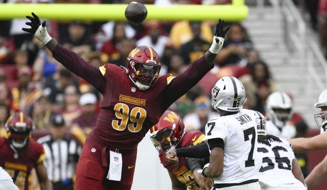 Washington Commanders defensive tackle Javon Kinlaw (99) pressures Las Vegas Raiders quarterback Geno Smith (7) during the second half of NFL football game Sunday, Sept. 21, 2025, in Landover, Md. (AP Photo/Nick Wass)