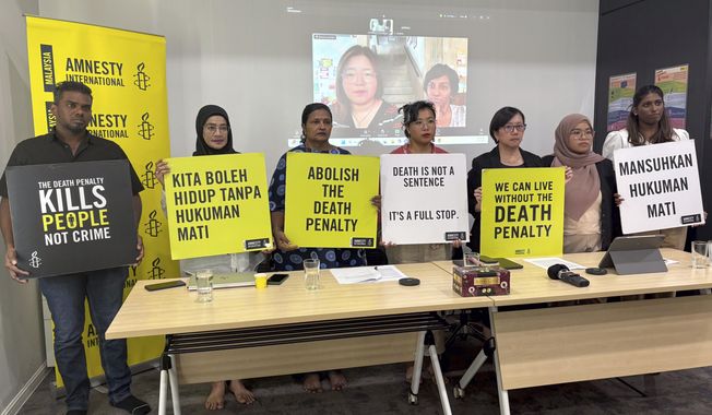 Nicole Fong, forth left, from Amnesty International Malaysia, holds a placard with others rights activists during a press conference in Kuala Lumpur, Malaysia, Monday, Sept. 22, 2025. (AP Photo/Eileen Ng)