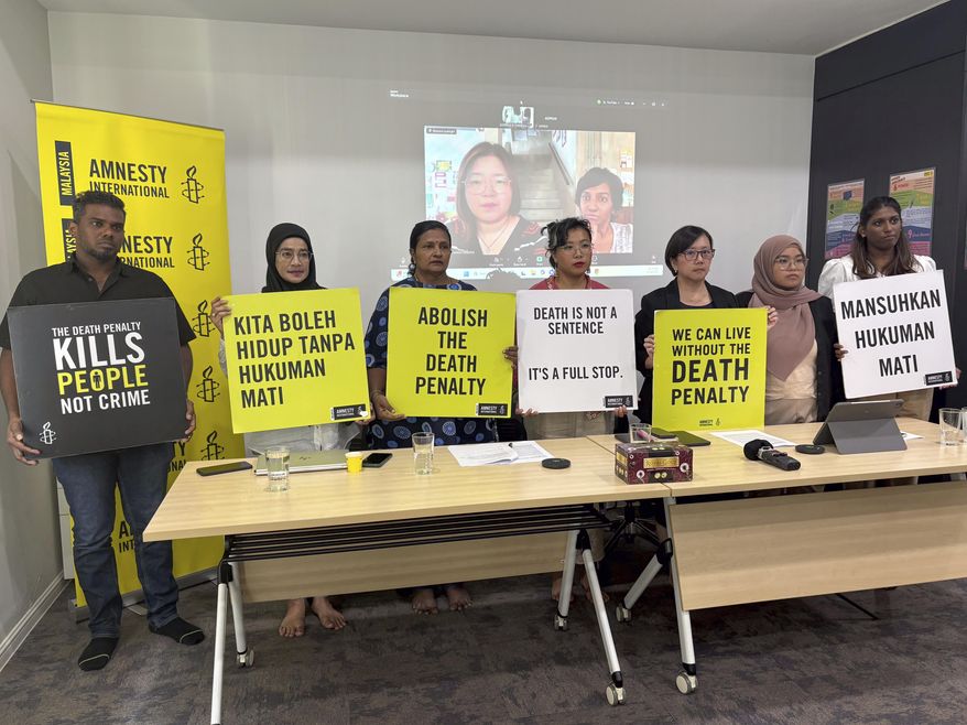 Nicole Fong, forth left, from Amnesty International Malaysia, holds a placard with others rights activists during a press conference in Kuala Lumpur, Malaysia, Monday, Sept. 22, 2025. (AP Photo/Eileen Ng)