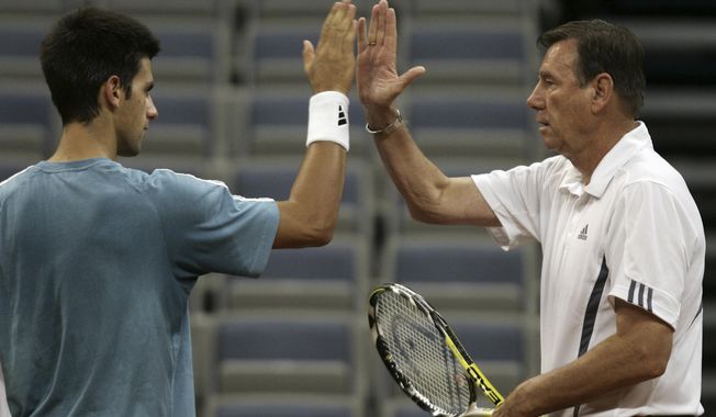 FILE - Serbian tennis player Novak Djokovic, left, high-fives captain Nikola Pilic during a practice session in Belgrade, Serbia, Wednesday, Sept. 19, 2007. (AP Photo/Darko Vojinovic, File)