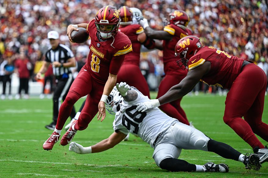 Washington Commanders quarterback Marcus Mariota (8) evades Las Vegas Raiders defensive tackle Jonah Laulu (96) en route to a two-yard touchdown run at Northwest Stadium in Landover, Maryland, September 21, 2025. (Photo by Brian Murphy for the Washington Times)