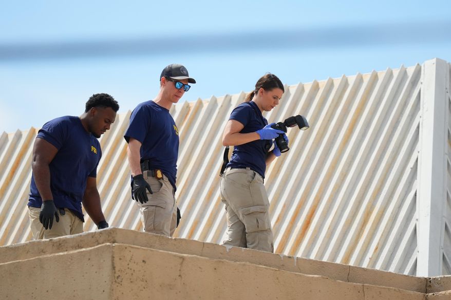 Law enforcement agents investigate the roof of an apartment building near the scene of a shooting at a U.S. Immigration and Customs Enforcement office in Dallas on Wednesday, Sept. 24, 2025. (AP Photo/Julio Cortez)