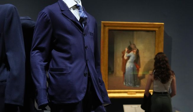 Giorgio Armani's creations are backdropped by the painting by Francesco Hayez titled "The Kiss", during the exhibition "Giorgio Armani - 50 Years" opened to the public at the Pinacoteca di Brera in Milan, Italy, Wednesday, Sept. 24 2025. (AP Photo/Antonio Calanni)