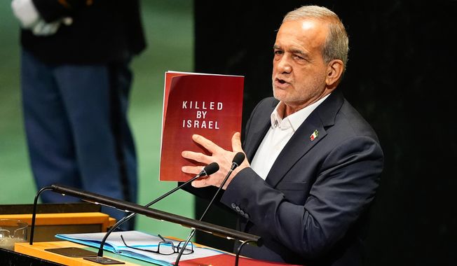 Iran President Masoud Pezeshkian holds up a book while speaking during the 80th session of the United Nations General Assembly, Wednesday, Sept. 24, 2025, at U.N. headquarters. (AP Photo/Yuki Iwamura)