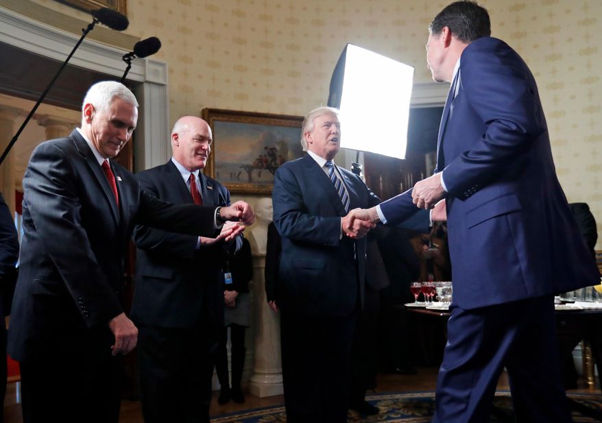 FILE - Vice President Mike Pence, left, and Secret Service Director Joseph Clancy stand as President Donald Trump shakes hands with FBI Director James Comey during a reception for inaugural law enforcement officers and first responders in the Blue Room of the White House, Jan. 22, 2017 in Washington. (AP Photo/Alex Brandon, File)