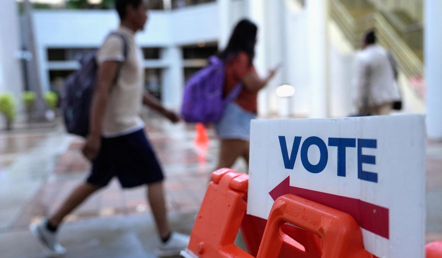 FILE - People walk past a "vote" sign on the first day of early voting in the general election in Miami, on Oct. 21, 2024. (AP Photo/Lynne Sladky, File)