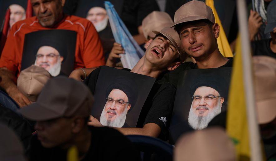 Hezbollah supporters weep as they hold images of Hezbollah leader Sayyed Hassan Nasrallah, who was killed in Israeli airstrikes, during a ceremony at Nasrallah's grave in Beirut, Lebanon, Saturday, Sept. 27, 2025, marking the first anniversary of his assassination. (AP Photo/Bilal Hussein)