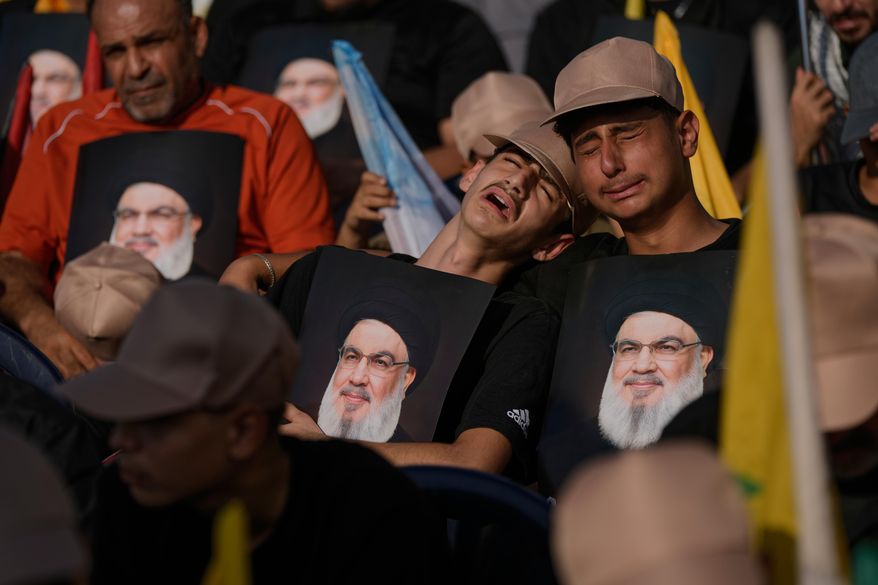 Hezbollah supporters weep as they hold images of Hezbollah leader Sayyed Hassan Nasrallah, who was killed in Israeli airstrikes, during a ceremony at Nasrallah's grave in Beirut, Lebanon, Saturday, Sept. 27, 2025, marking the first anniversary of his assassination. (AP Photo/Bilal Hussein)