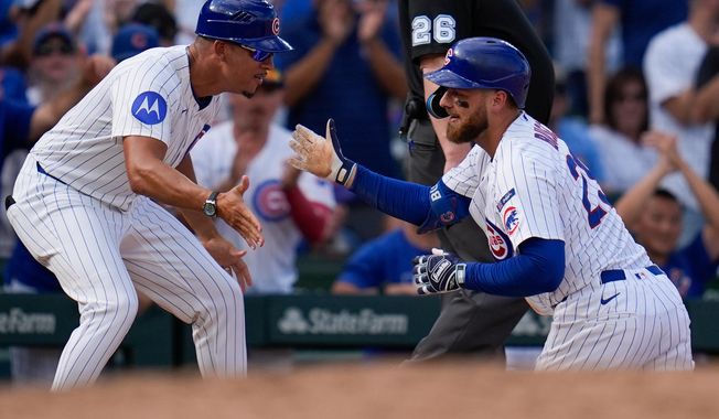 Chicago Cubs' Michael Busch, right, high-fives third base coach Quintin Berry (0) after hitting a triple during the seventh inning of a baseball game against the St. Louis Cardinals, Saturday, Sept. 27, 2025, in Chicago. (AP Photo/Erin Hooley)