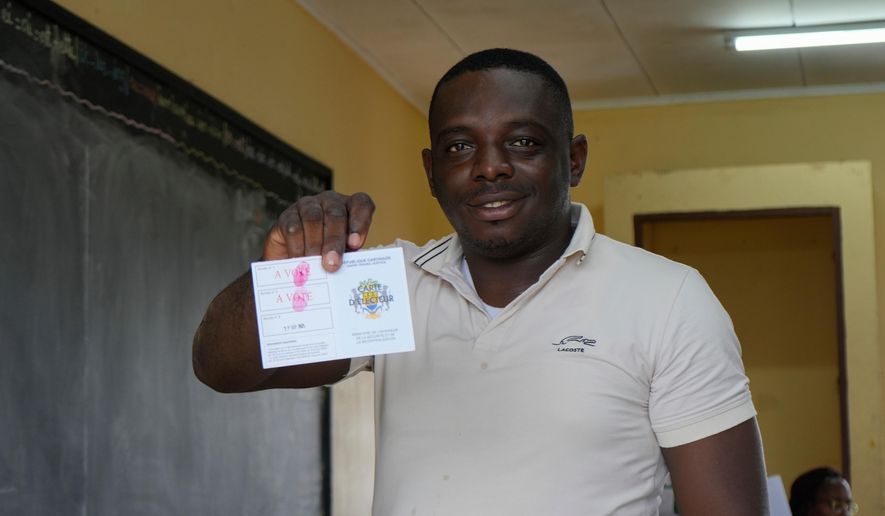 A voter displays his stamped voter card after casting his ballot at a polling station in Libreville, Gabon, Saturday, Sept. 27, 2025. (AP Photo/Betines Makosso)