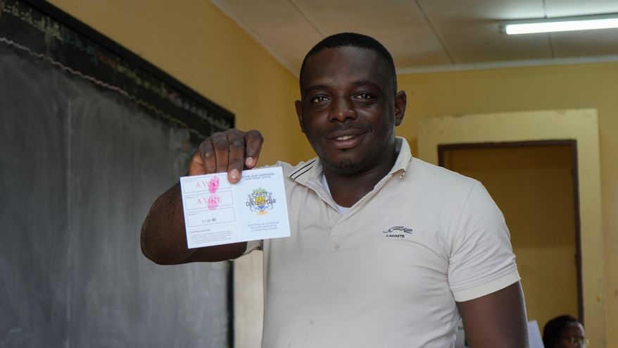 A voter displays his stamped voter card after casting his ballot at a polling station in Libreville, Gabon, Saturday, Sept. 27, 2025. (AP Photo/Betines Makosso)