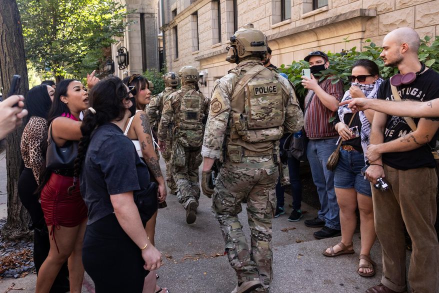 Pedestrians yell at federal agents from U.S. Immigration and Customs Enforcement and U.S. Customs and Border Protection as they walk along North Clark Street near West Oak Street in the River North neighborhood, Sunday, Sept. 28, 2025, in Chicago. (Ashlee Rezin/Chicago Sun-Times via AP)