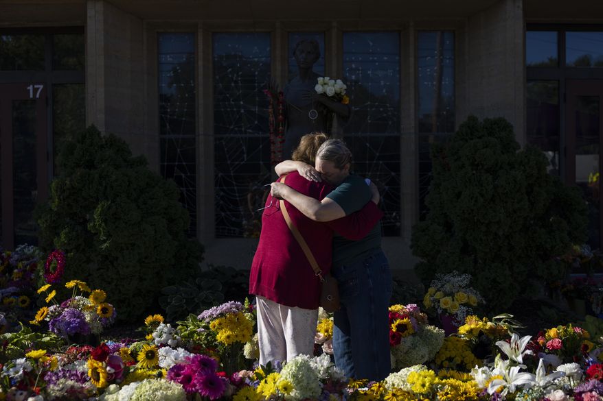 Women embrace at the memorial outside the Annunciation Catholic Church following Wednesday's shooting at the school, Sunday, Aug. 31, 2025, in Minneapolis. (AP Photo/Ellen Schmidt)