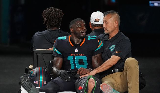 Miami Dolphins wide receiver Tyreek Hill (10) talks with a staff member as he is carted off the field after suffering an unknown lower leg injury in the second half of an NFL football game against the New York Jets, Monday, Sept. 29, 2025, in Miami Gardens, Fla. (AP Photo/Rebecca Blackwell)