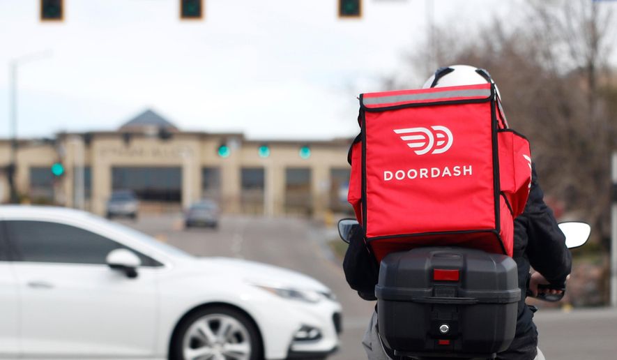 A food delivery rider waits for the traffic light to change in Lone Tree, Colo., on Monday, March 30, 2020. (AP Photo/David Zalubowski) ** FILE **