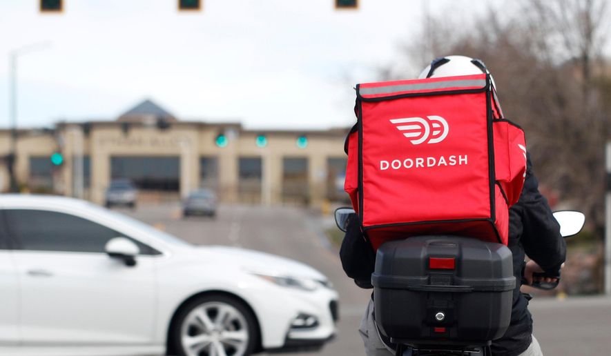 A food delivery rider waits for the traffic light to change in Lone Tree, Colo., on Monday, March 30, 2020. (AP Photo/David Zalubowski) **FILE**