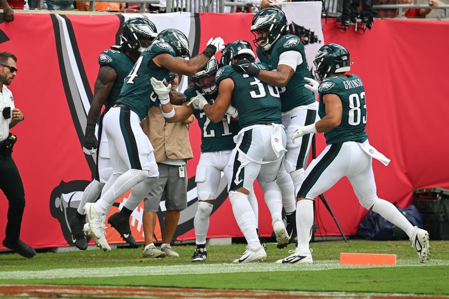 Philadelphia Eagles teammates surround safety Sydney Brown (21) as they celebrate his touchdown during the first half of an NFL football game against the Tampa Bay Buccaneers, Sunday, Sept. 28, 2025, in Tampa, Fla. (AP Photo/Jason Behnken)