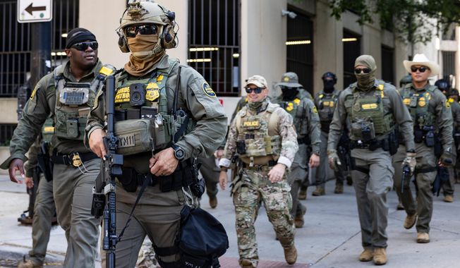 Federal agents from U.S. Immigration and Customs Enforcement and U.S. Customs and Border Protection walk north on North Clark Street in the River North neighborhood, Sunday, Sept. 28, 2025, in Chicagp. (Ashlee Rezin/Chicago Sun-Times via AP)