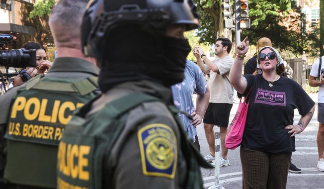 Pedestrians yell at federal agents from U.S. Immigration and Customs Enforcement and U.S. Customs and Border Protection as they stand on North Clark Street at West Oak Street in River North, Sunday, Sept. 28, 2025, in Chicago. (Ashlee Rezin/Chicago Sun-Times via AP)
