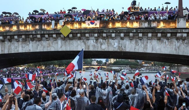 FILE - French athletes wave flags as they sail in a boat on the Seine River during the opening ceremony for the 2024 Summer Olympics in Paris, France, Friday, July 26, 2024. (Franck Fife/Pool Photo via AP, File)