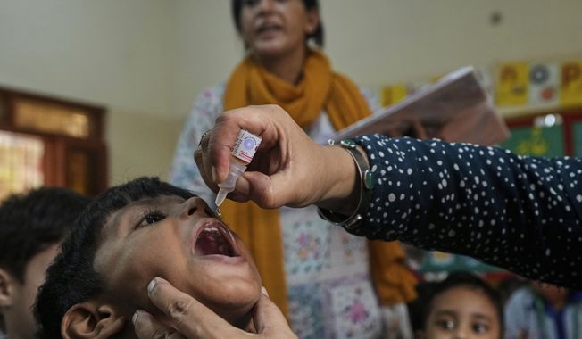 A health worker administers a polio vaccine to a child in a school, in Karachi, Pakistan, Monday, Sept. 1, 2025. (AP Photo/Fareed Khan)