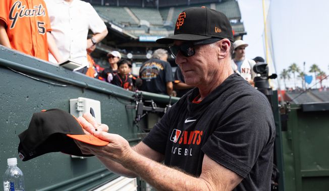 San Francisco Giants manager Bob Melvin gives out autographs before an MLB baseball game against the Colorado Rockies, Saturday, Sept. 27, 2025, in San Francisco. (AP Photo/Benjamin Fanjoy)