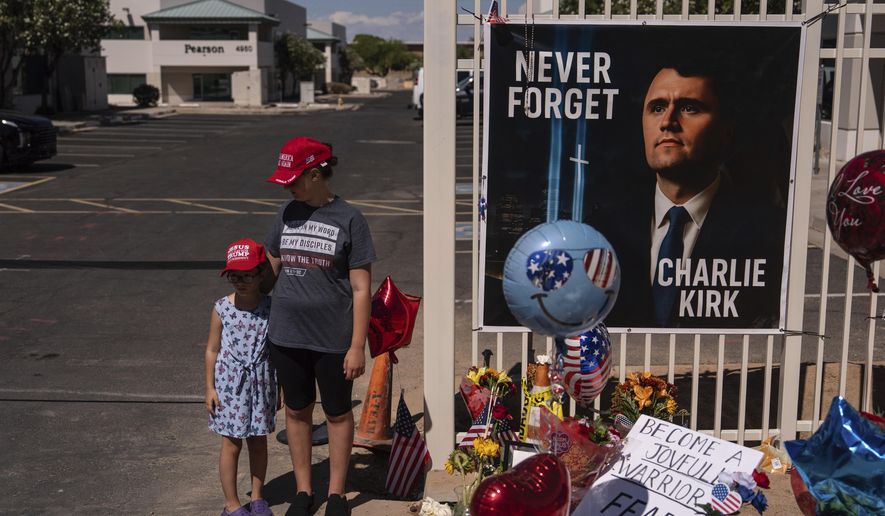 Nicole and Amalia, who asked to be identified by their first names only, stand for a photo at a makeshift memorial for Charlie Kirk outside Turning Point USA headquarters in Phoenix Saturday, Sept. 20, 2025. (AP Photo/Jae C. Hong)