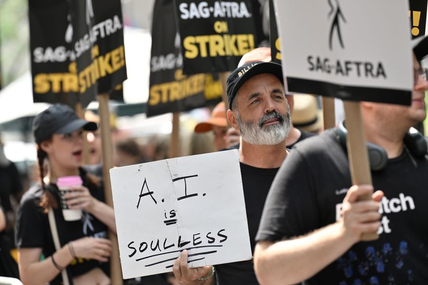 SAG-AFTRA picketers carry signs outside NBC in Rockefeller Center on July 17, 2023, in New York. (Photo by Evan Agostini/Invision/AP, File)
