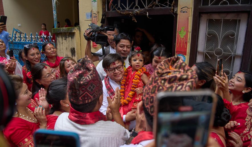 Nepal's newly appointed living goddess, Kumari Aryatara Shakya, is carried by her family member as they get ready to walk towards Kumari Ghar, the temple palace where she will be residing in Kathmandu, Nepal, Tuesday, Sept. 30, 2025. (AP Photo/Niranjan Shrestha)