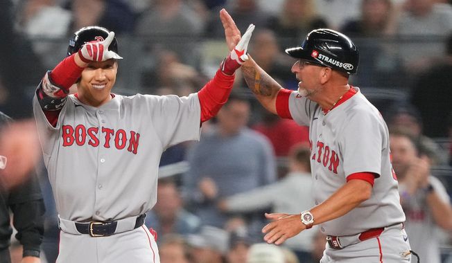 Boston Red Sox outfielder Masataka Yoshida, left, celebrates with first base coach José David Flores after driving in two runs against the New York Yankees during the seventh inning of Game 1 of an American League wild-card baseball playoff series, Tuesday, Sept. 30, 2025, in New York. (AP Photo/Yuki Iwamura)
