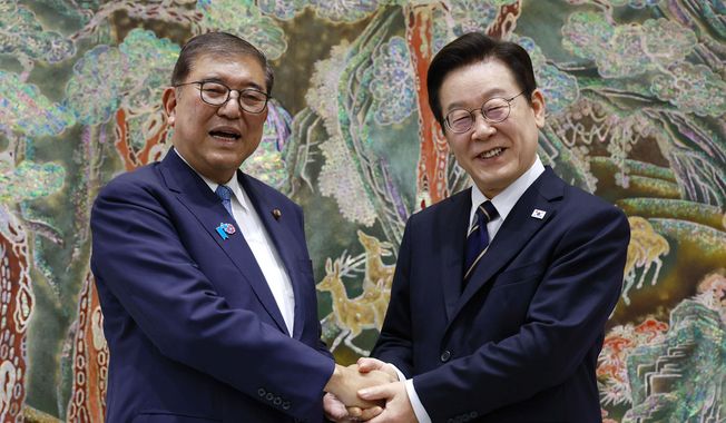 South Korean President Lee Jae-myung, right, shakes hands with Japanese Prime Minister Shigeru Ishiba, left, during a meeting in Busan, South Korea, Tuesday, Sept. 30, 2025. (Yonhap via AP)