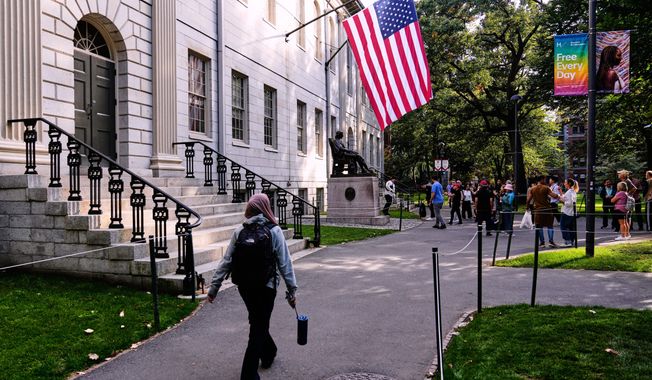 A woman walks through Harvard Yard at Harvard University, Tuesday, Sept. 30, 2025, in Cambridge, Mass. (AP Photo/Charles Krupa)