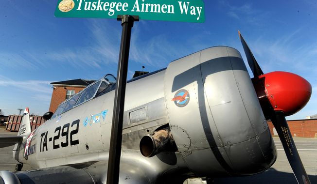 FILE - The Tuskegee Airmen Way street sign is briefly displayed in front of a 1943 North American T6 Texan aircraft used to train pilots during WWII, at the Selfridge Air National Guard Base, in Harrison Township, Mich., Feb. 27, 2018. (Todd McInturf/Detroit News via AP, File)