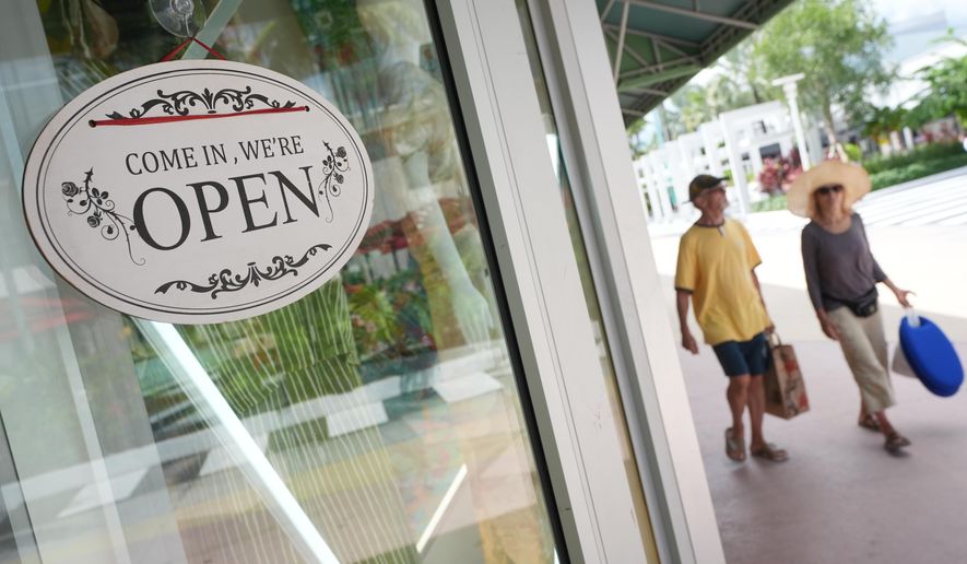 Shoppers walk by a clothing store, Thursday, Sept. 25, 2025, in Miami Beach, Fla. (AP Photo/Marta Lavandier)
