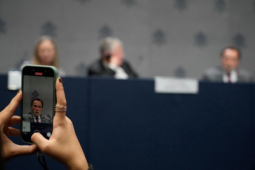 A journalist scans with his phone former California Gov. Arnold Schwarzenegger during a press conference at the Vatican, Tuesday, Sept. 30, 2025, to present the "Raising Hope for Climate Justice Conference," promoted by the Laudato Si' (Praise Be to You) Movement, which was inspired by the late Pope Francis' encyclical letter of the same name. (AP Photo/Gregorio Borgia)