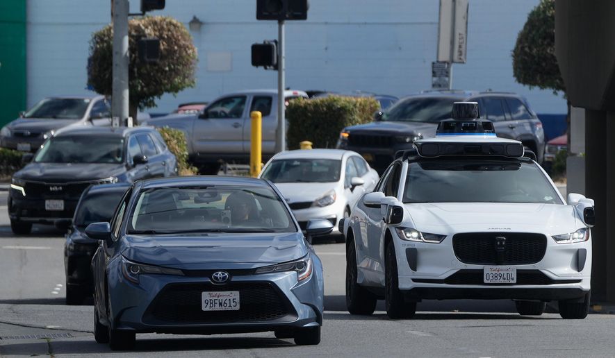 A Waymo vehicle, right, drives in San Bruno, Calif., Tuesday, Sept. 30, 2025. (AP Photo/Jeff Chiu)