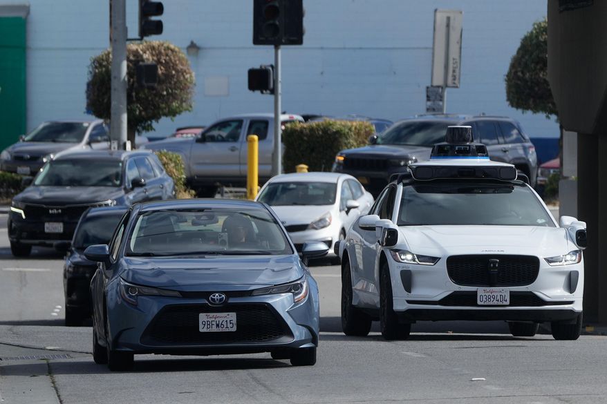A Waymo vehicle, right, drives in San Bruno, Calif., Tuesday, Sept. 30, 2025. (AP Photo/Jeff Chiu)